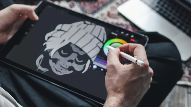 A person using a stylus to draw a stylised skull with a beanie on a digital tablet.
